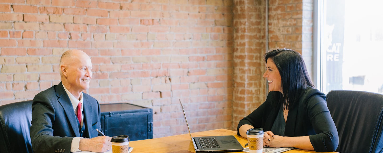 An insurance broker and a client talking across a meeting-room table